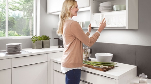 Vrouw pakt glas uit keuken